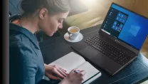 Woman writing at desk with notepad coffee and laptop